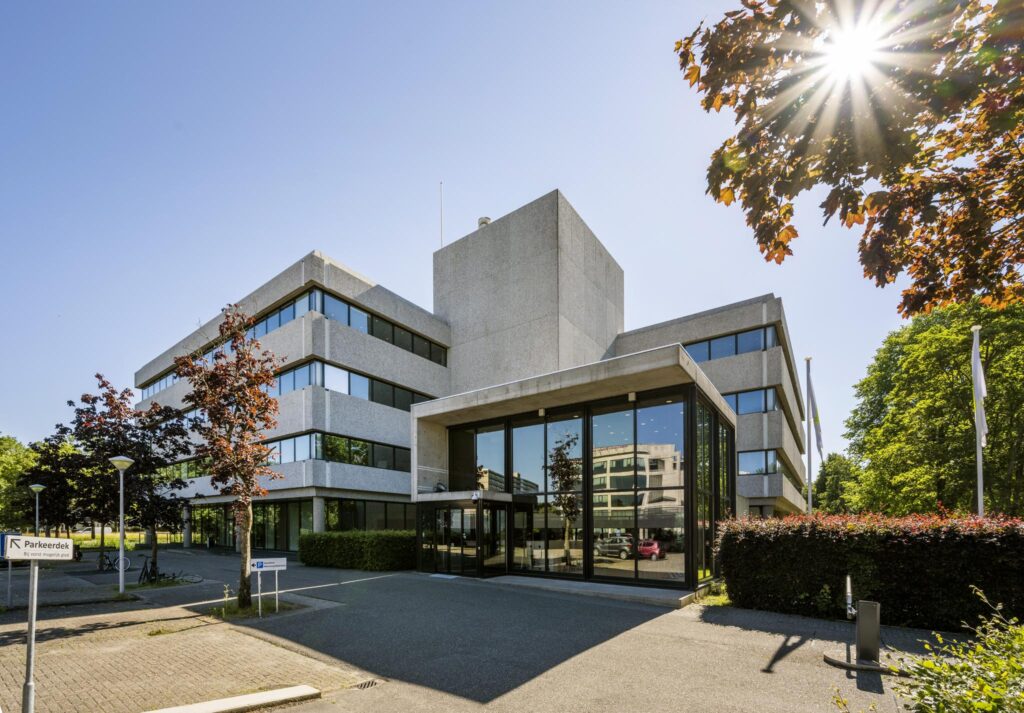 Modern office building on Prof. E.M. Meijerslaan with large glass entrance and surrounding greenery under a clear blue sky.